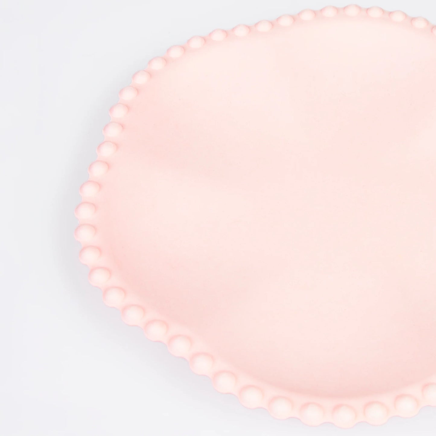 Close-up of pink scalloped paper plate with beaded edge detail