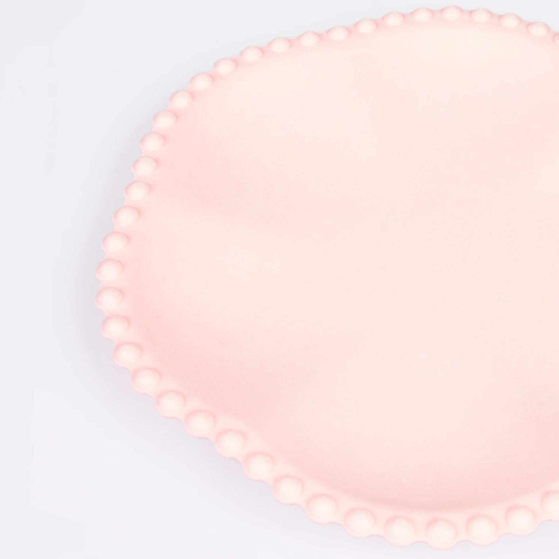 Close-up of pink scalloped paper plate with beaded edge detail