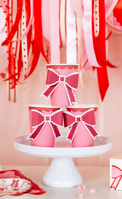 Pink bow party cups styled on a white cake stand for a Valentine’s Day celebration, available in Toronto at Confetti My Party