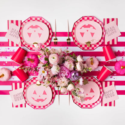 Pink Halloween party table with jack-o'-lantern plates, checkerboard plates and pink party decor
