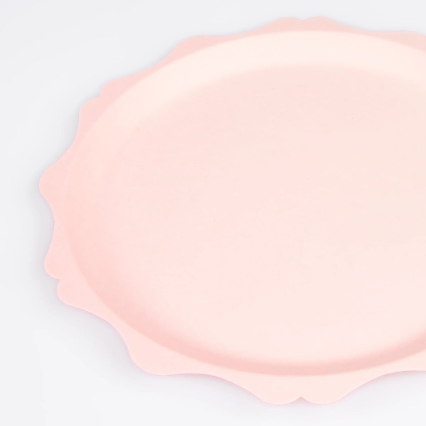 Close-up of blush pink scalloped paper plate with soft curved edges