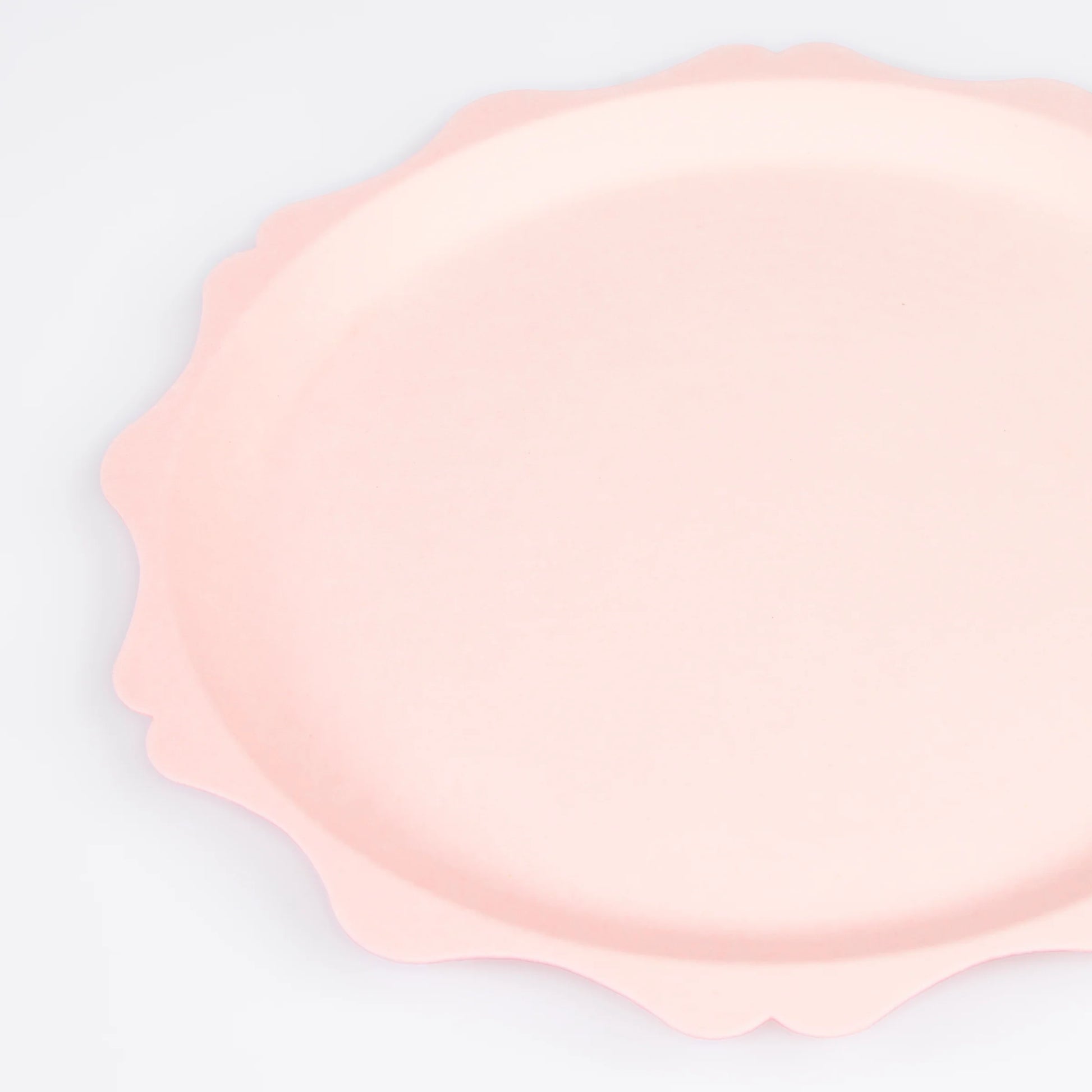 Close-up of blush pink scalloped paper plate with soft curved edges
