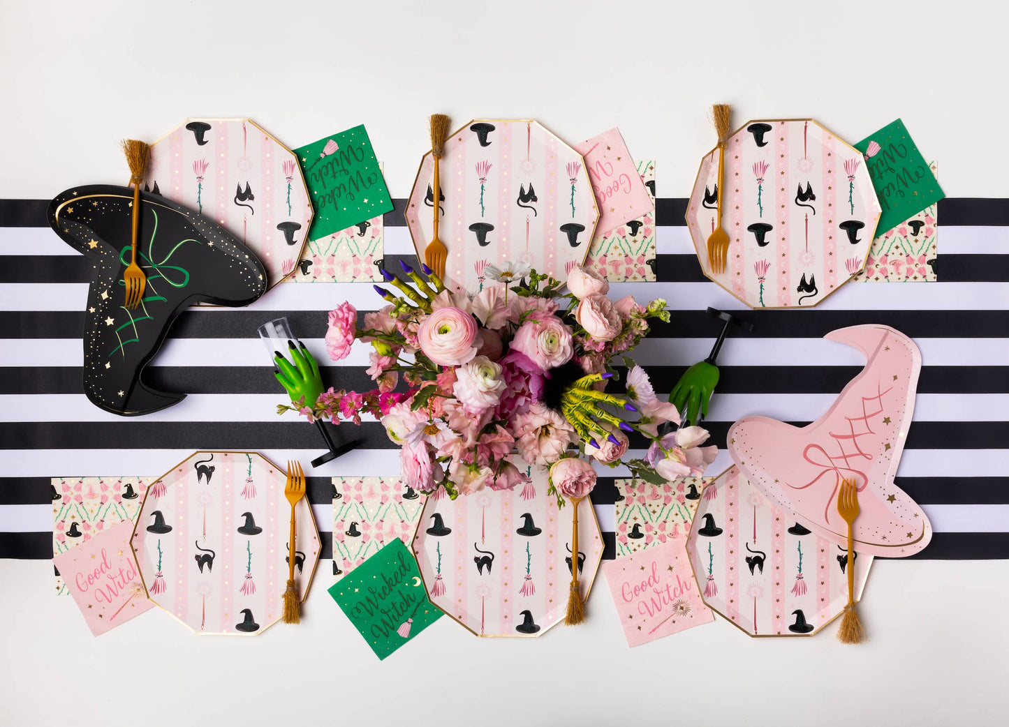 Pink witch themed Halloween party table with witch hat plates, patterned plates, napkins and gold