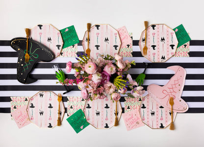 Pink witch themed Halloween party table with witch hat plates, patterned plates, napkins and gold
