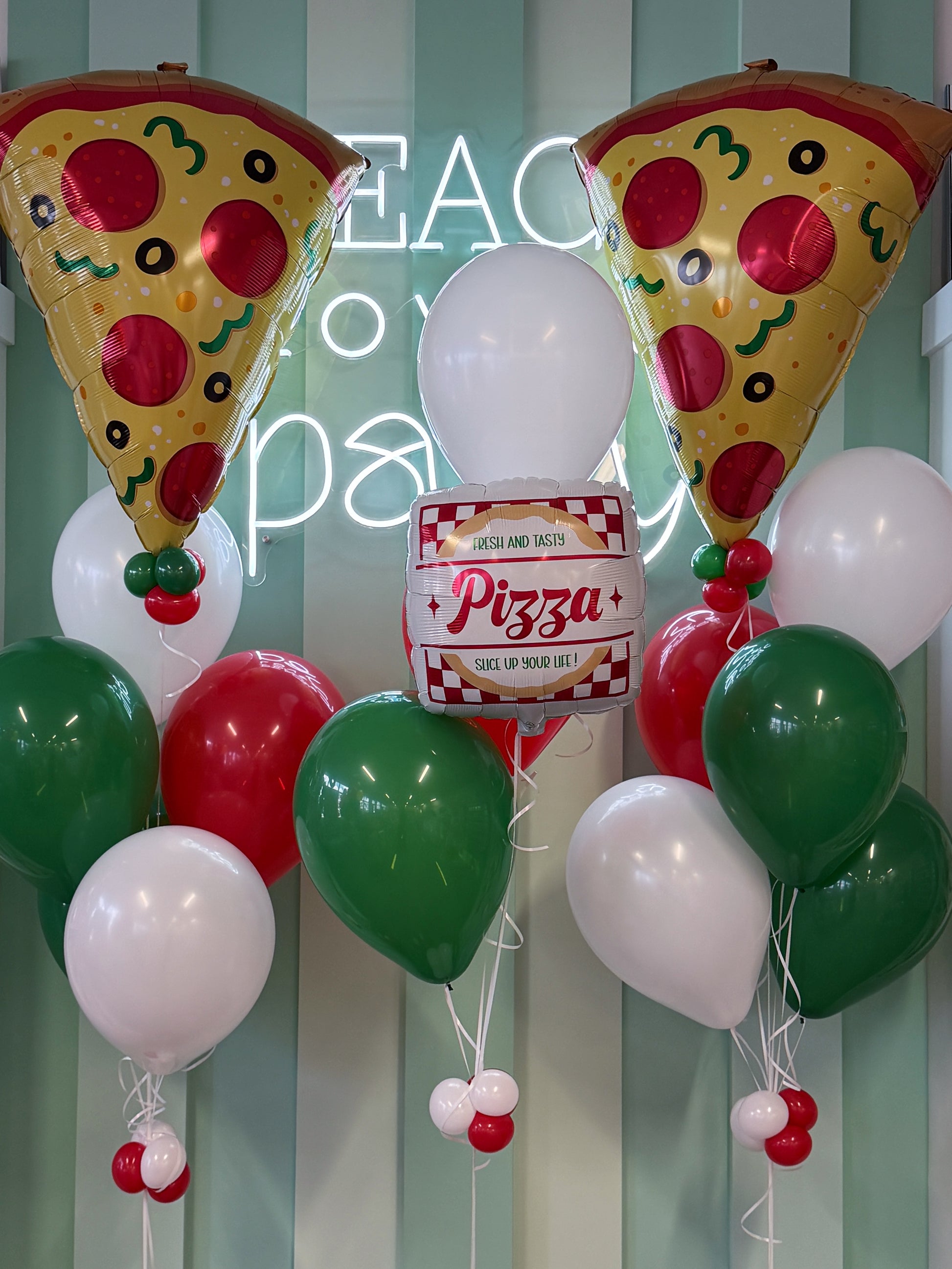 Pizza birthday balloon arrangement with two giant pizza slice balloons, pizza box balloon and red, green and white balloons in Toronto.