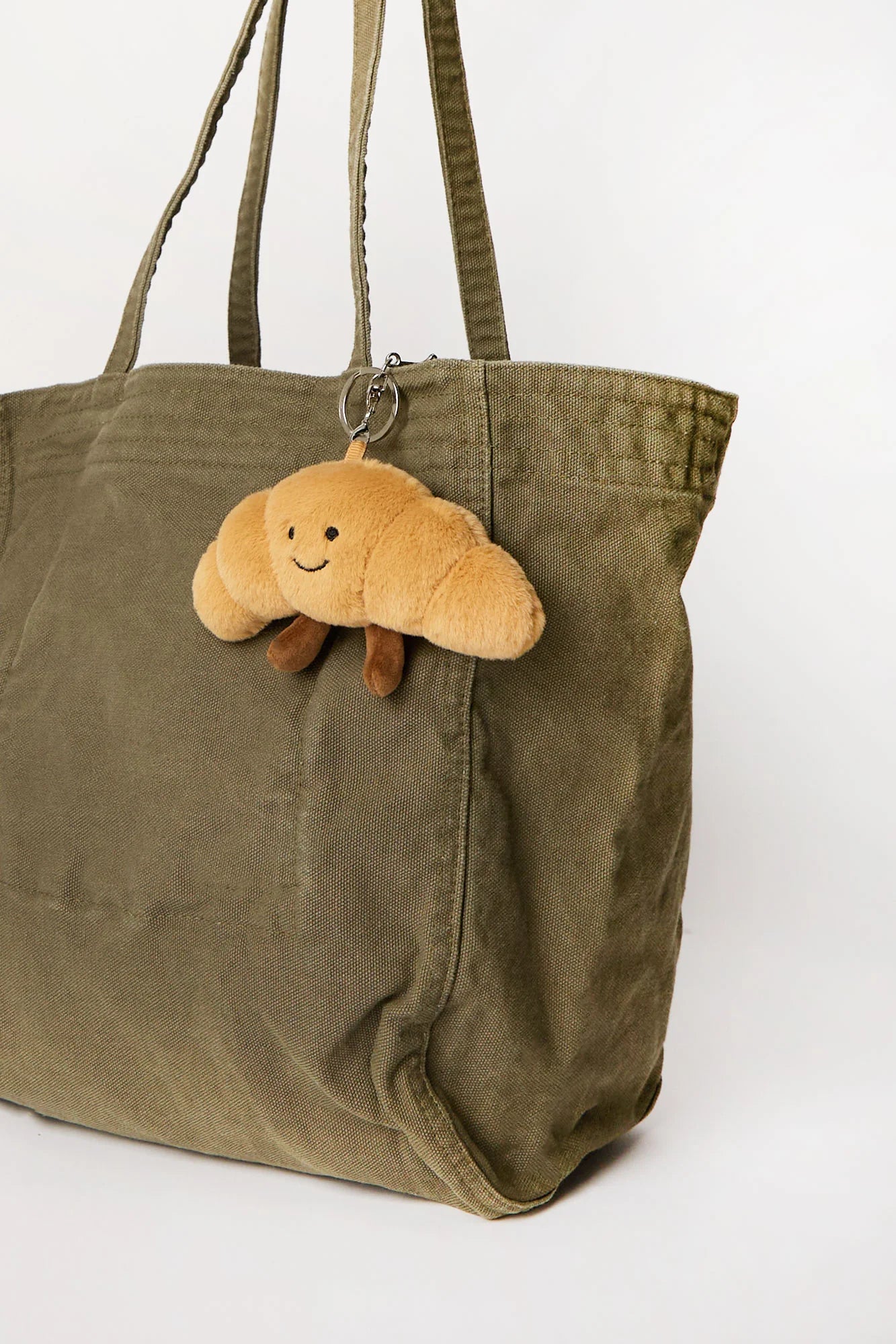 Croissant plush keychain charm clipped onto bag available in Toronto and shipping across Canada