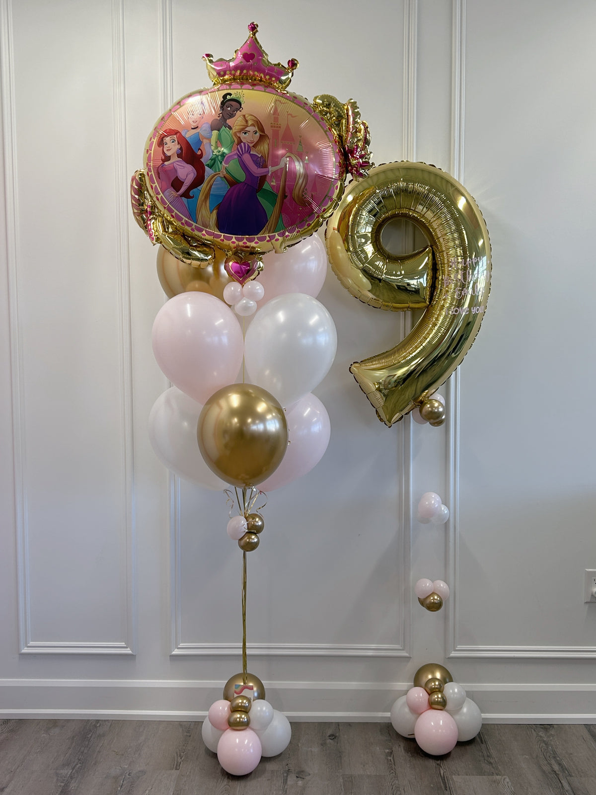 Full Disney Princess birthday balloon bundle with a large princess foil balloon, personalized gold number 9, pastel pink and white latex balloons and decorative balloon bases.