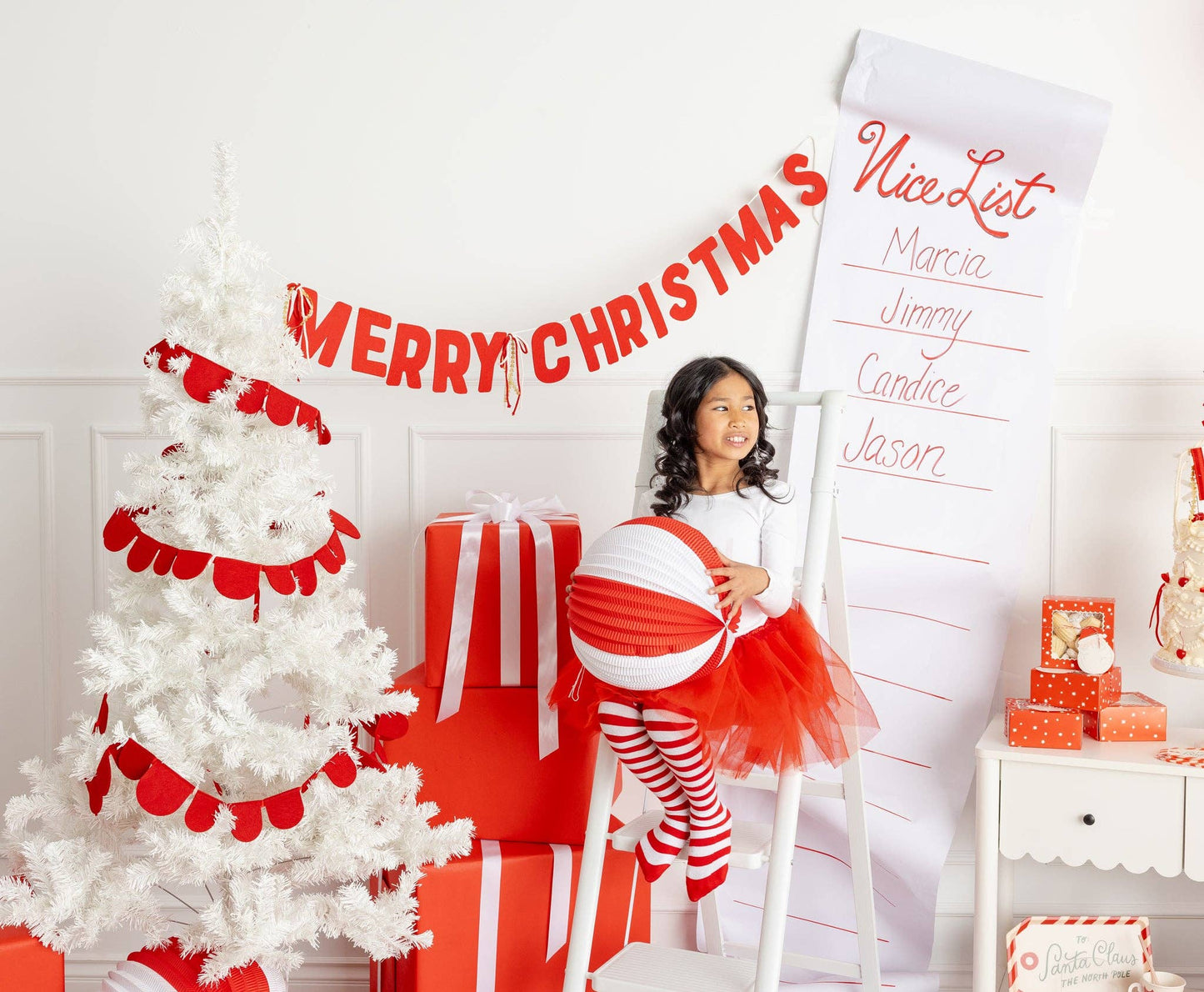 Christmas setup with red felt Merry Christmas banner, white tree, and red wrapped gifts, perfect for Canada-wide celebrations.