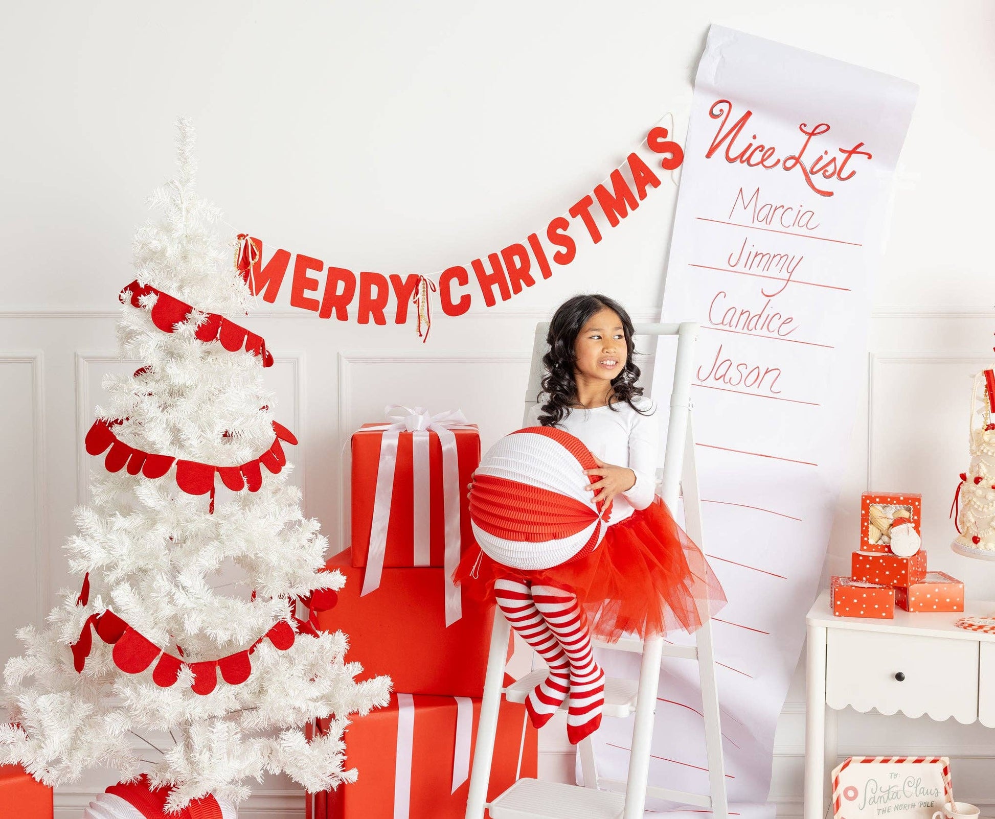 Christmas setup with red felt Merry Christmas banner, white tree, and red wrapped gifts, perfect for Canada-wide celebrations.