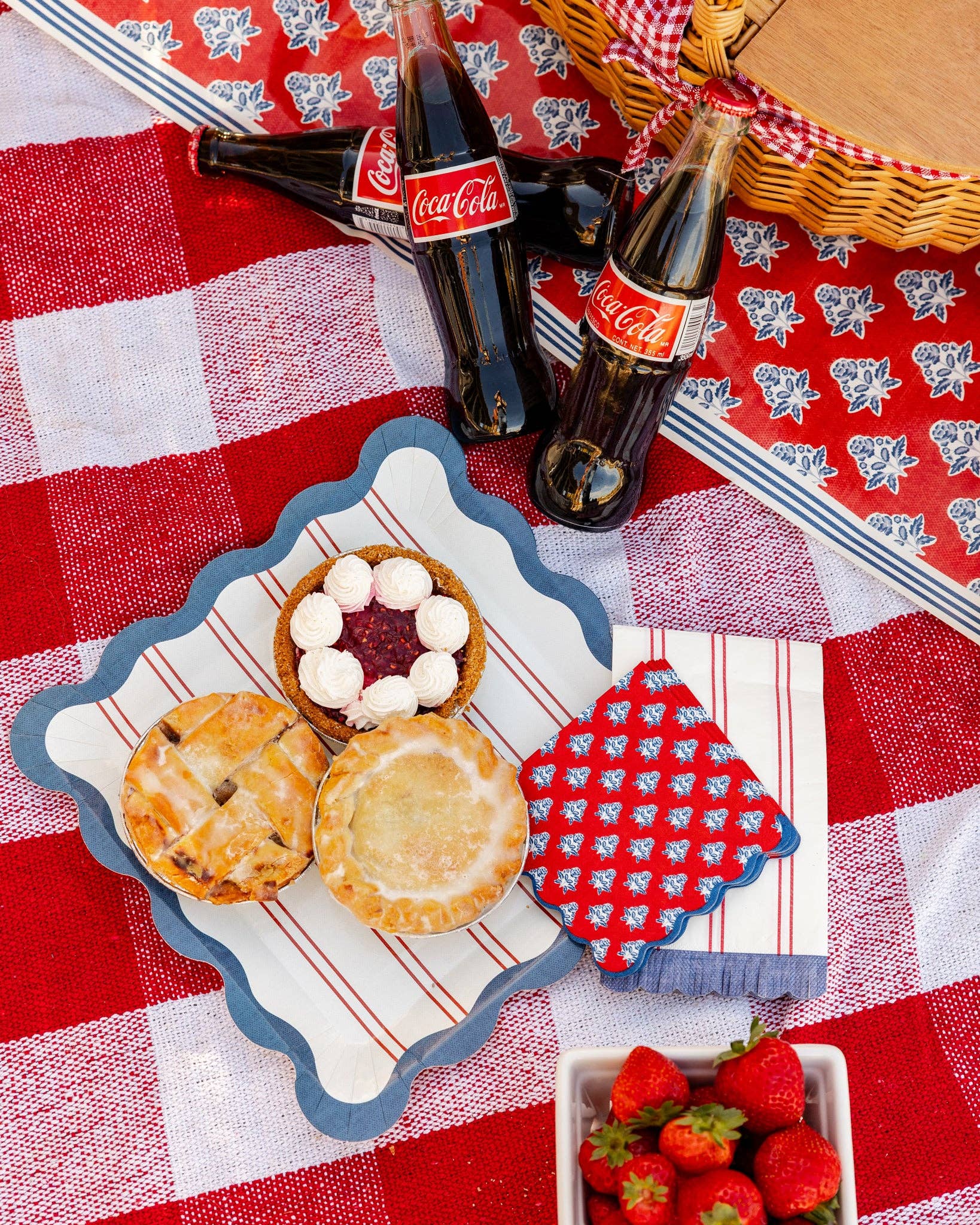 Biscuits, strawberries, and Coca-Cola bottles on a red checkered tablecloth