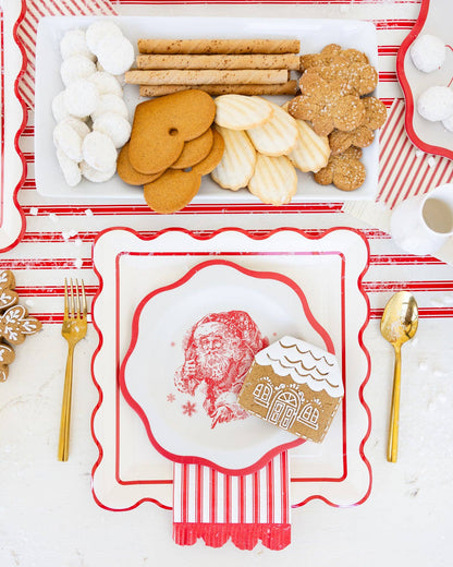 Christmas-themed table setting with gingerbread cookies, marshmallows, and a decorative card featuring Santa Claus and a gingerbread house.