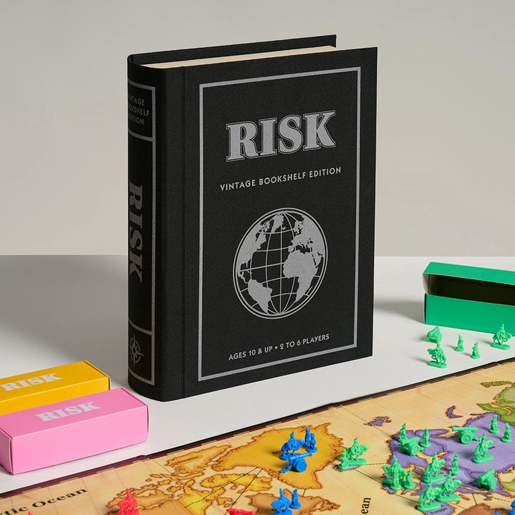 Vintage bookshelf edition of the Risk board game with game pieces and map on a light surface.