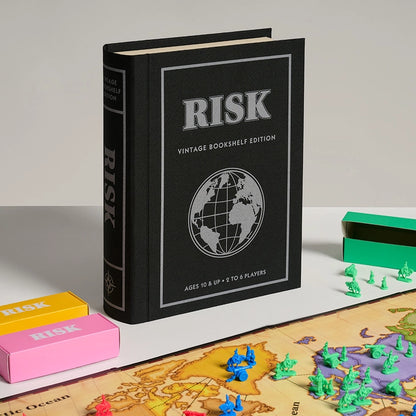 Vintage bookshelf edition of the Risk board game with game pieces and map on a light surface.