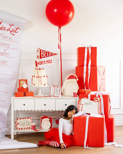 Red and white Christmas table styled with Santa scroll placemat, holiday cake and gift boxes in Toronto.