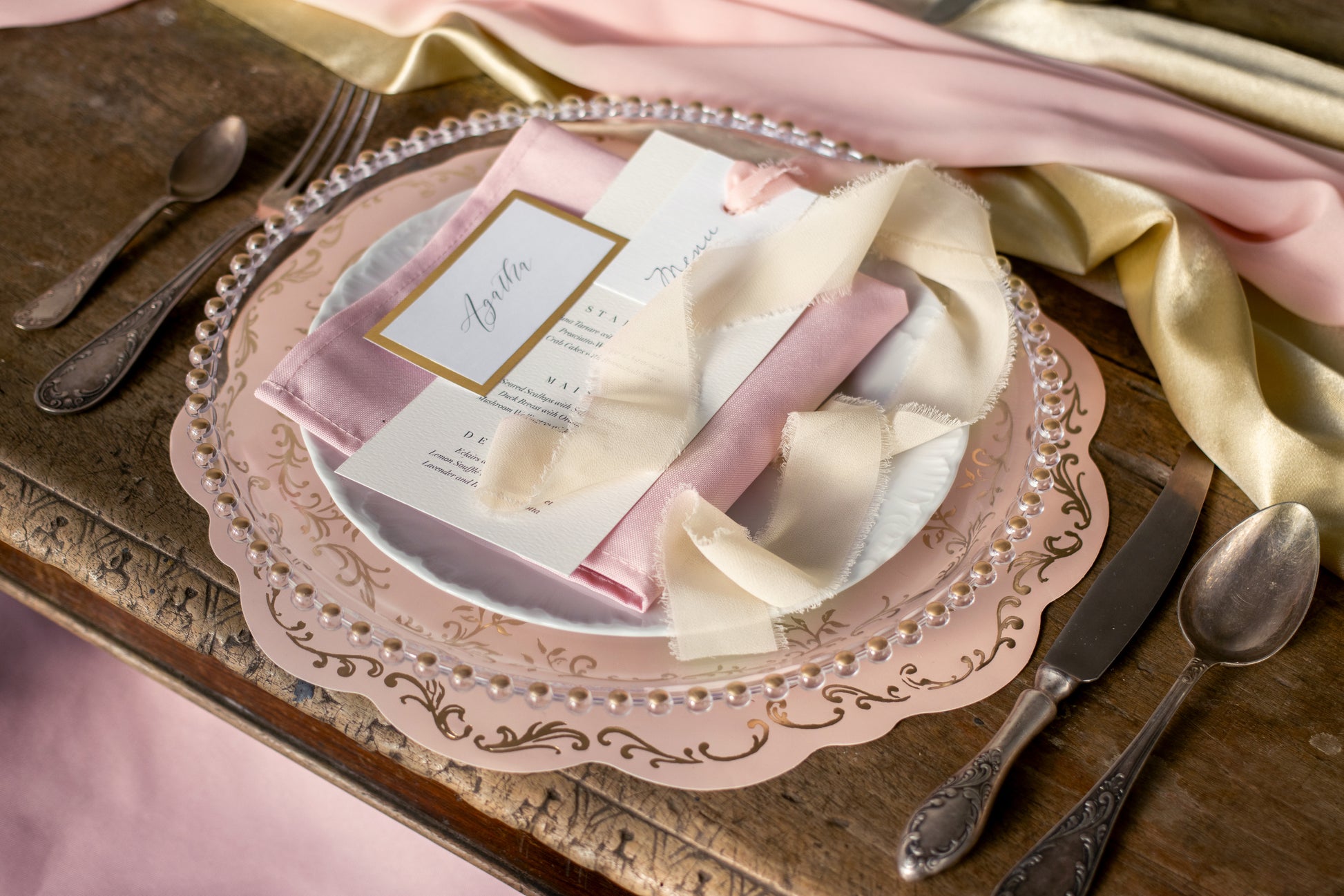 scalloped pink and hold placemats set with glass plate and menu card