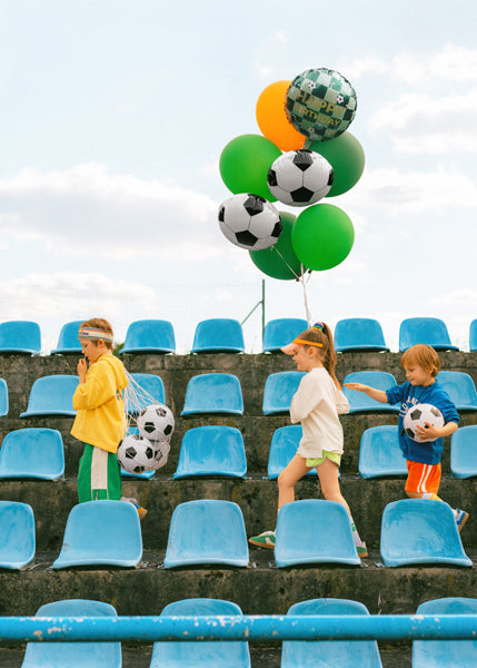 Kids holding soccer Happy Birthday foil balloon bouquet in Toronto birthday party setting.