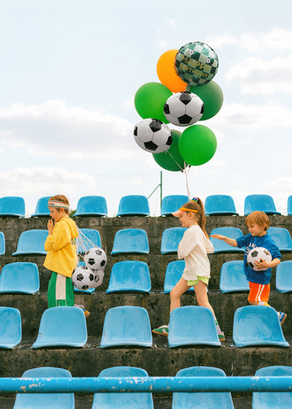 Kids holding soccer Happy Birthday foil balloon bouquet in Toronto birthday party setting.