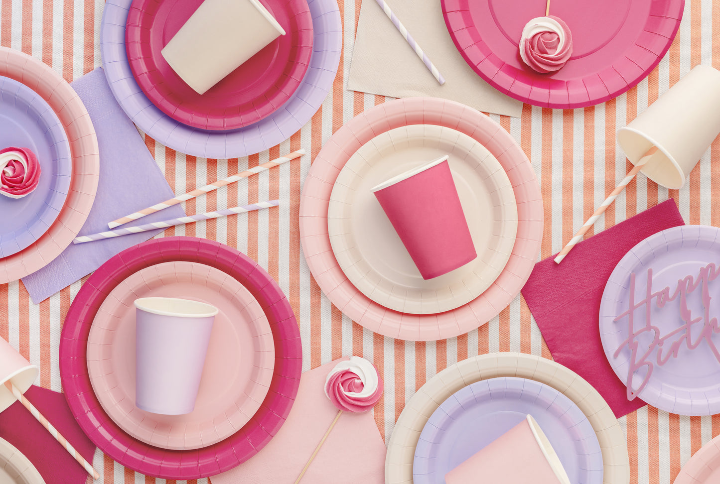 Colorful paper plates and cups on a striped background