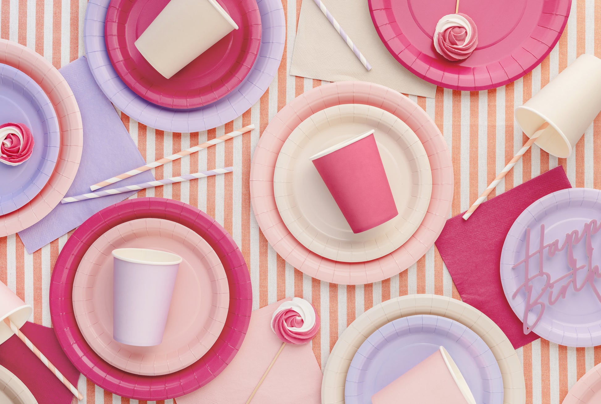 Colorful paper plates and cups on a striped background