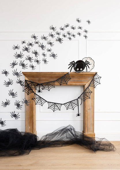 Halloween fireplace decor with spider webs and black cobwebs on a white wall.