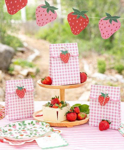 Strawberry birthday treat bags styled on a pink gingham party table