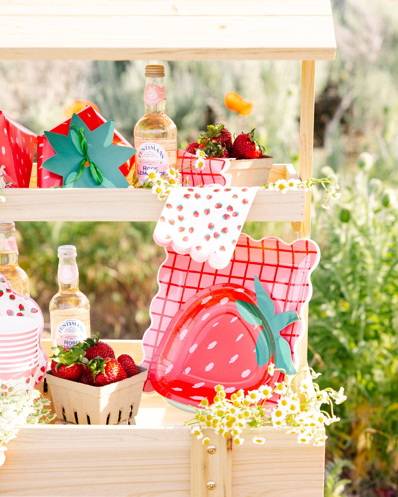 Strawberry-themed table setup with patterned napkins, treat boxes, and red fruit décor in Toronto.