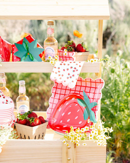 Strawberry-themed table setup with patterned napkins, treat boxes, and red fruit décor in Toronto.