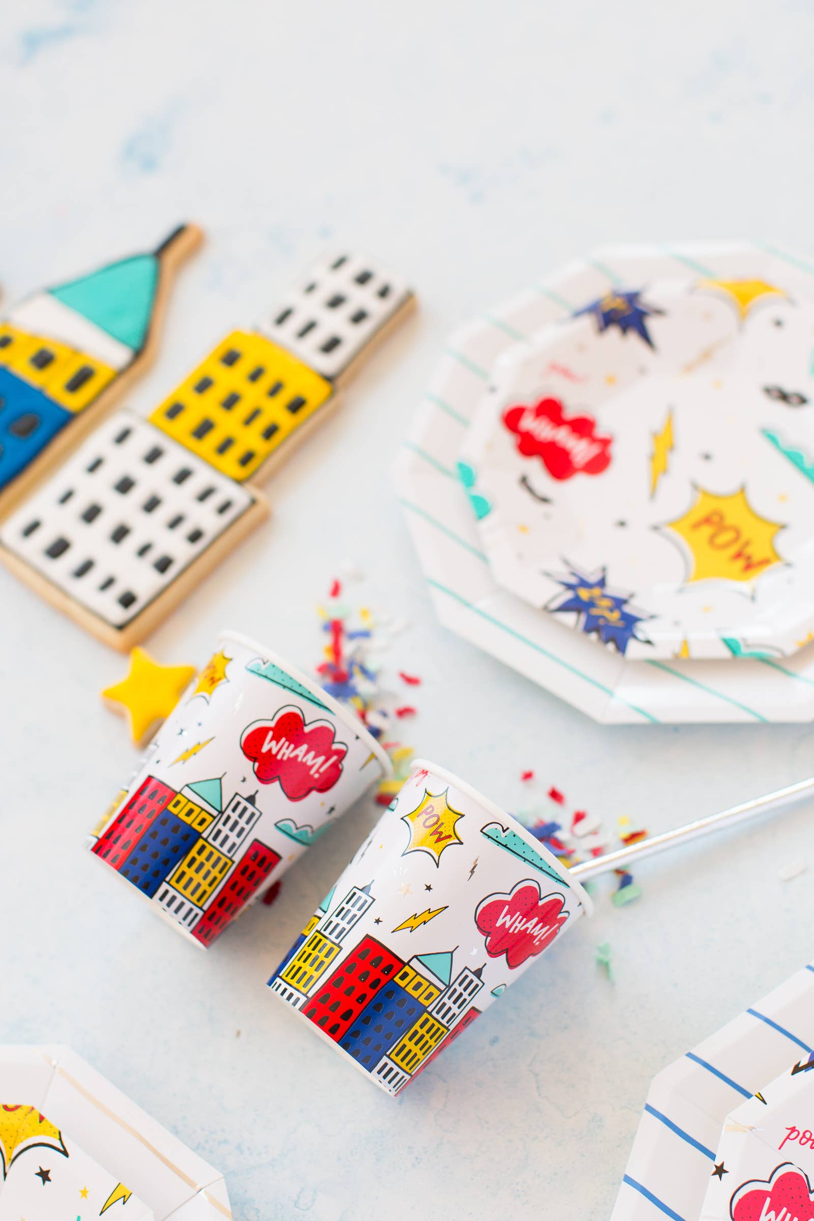 Comic-style superhero paper cups with colourful cityscape design styled with matching party plates from Confetti My Party Toronto