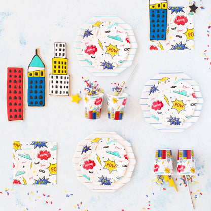 Superhero party table setup featuring comic-style napkins, plates, and cups with bold graphic designs from Confetti My Party Toronto