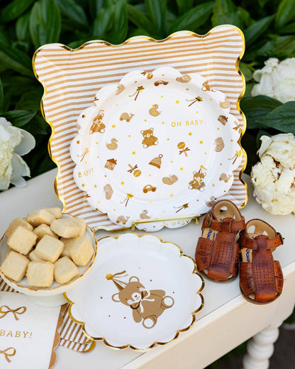 Layered Oh Baby party plates with teddy bear and striped gold designs, styled for Toronto baby showers.