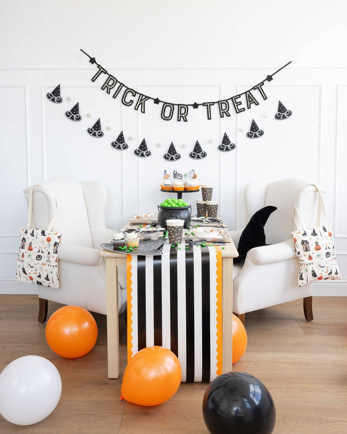 Halloween-themed room with a table set for a celebration, balloons, and decorations.