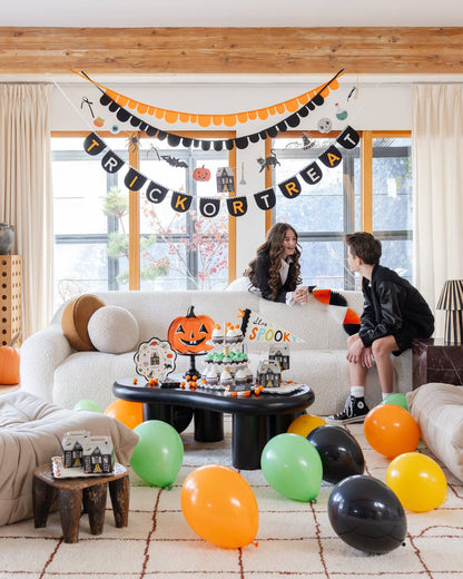Trick or Treat felt banner hanging in a Halloween party setup with orange and black decorations