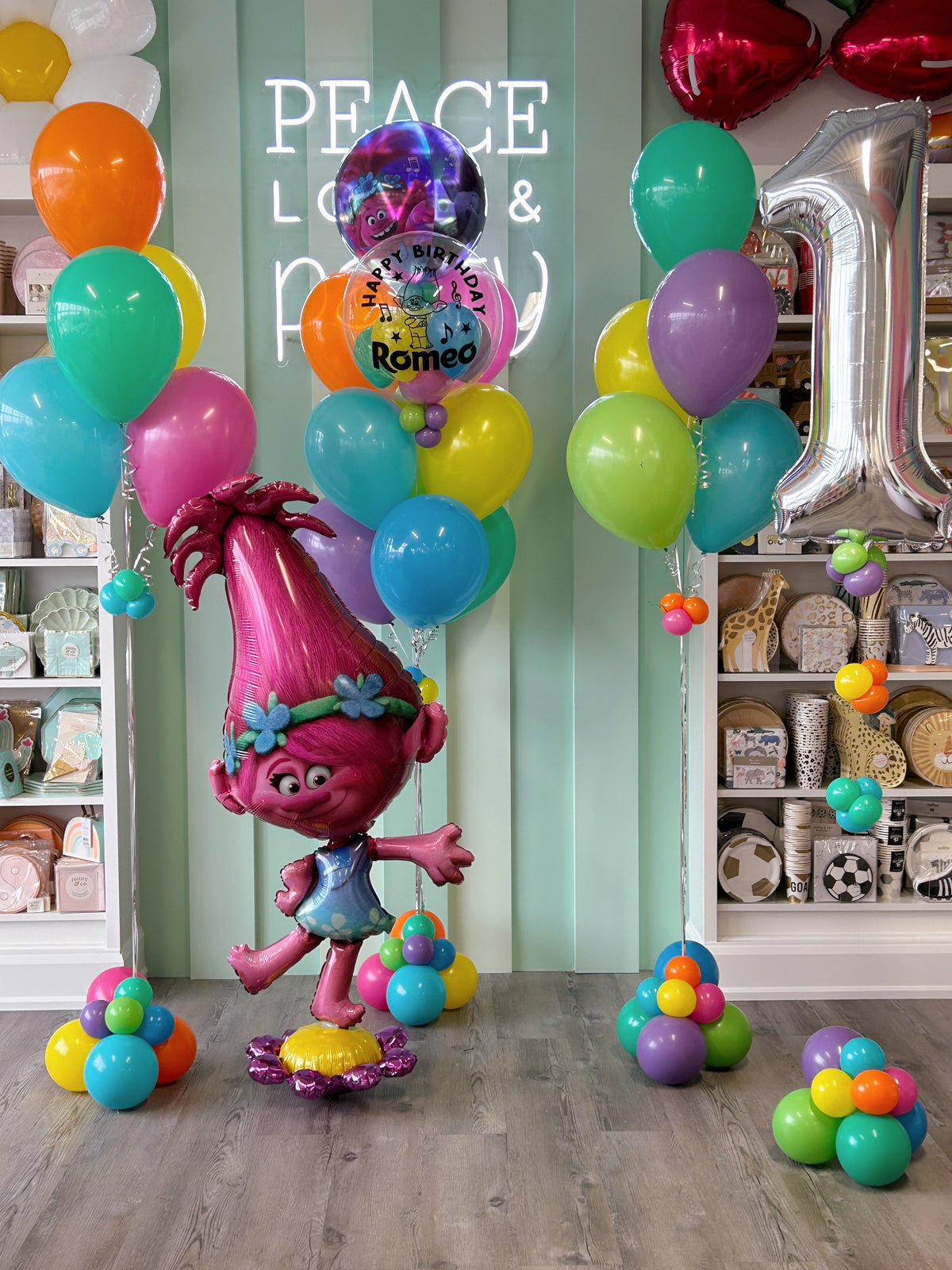 Colourful Trolls first birthday balloon setup with Poppy character balloon, personalized bubble, silver number 1 and rainbow helium balloon bouquets in Toronto.