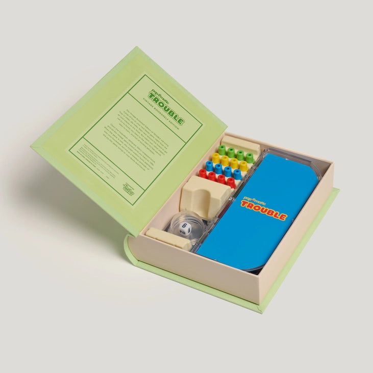 Open box containing Trouble board game with colourful pieces and a blue tray on a light gray background.