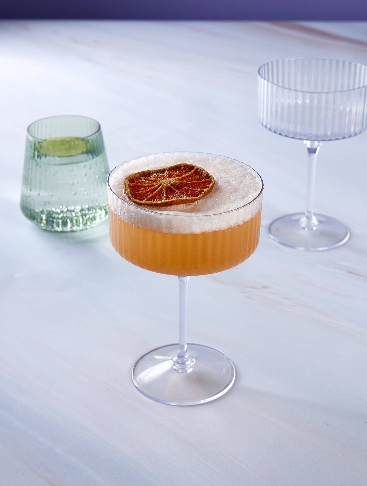 Ribbed plastic coupe glass with cocktail displayed on a table, sold at Confetti My Party Toronto.