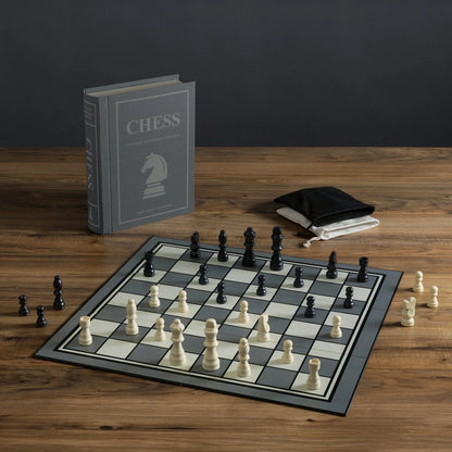 Chessboard with pieces and a book titled 'Chess' on a wooden surface.