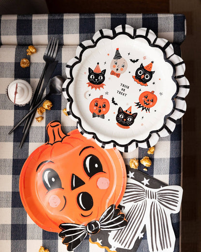 Halloween-themed plate with pumpkins and cats on a checkered tablecloth.