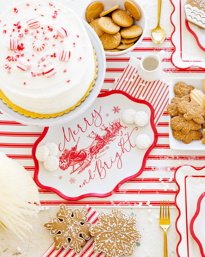Christmas-themed table setting with cookies, cake, and decorative 'Merry and Bright tray on a red and white striped tablecloth.