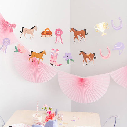 Decorative wall with horse-themed decorations including paper fans, ribbons, and cowboy hats on a light gray background.