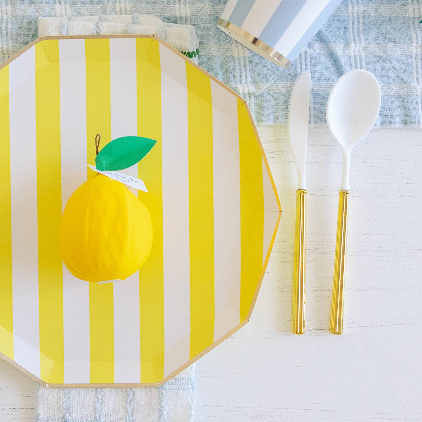 Yellow and white striped placemat with a lemon design on a table setting.