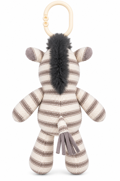 Back view of cream and taupe knitted zebra stroller plush showing its dark grey fluffy mane, striped body, tassel tail and ivory attachment ring.