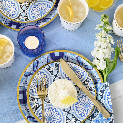 Amalfi Blues large paper plates styled in a Mediterranean tablescape with blue linens, gold cutlery, and lemon desserts, available in Toronto and shipping across Canada