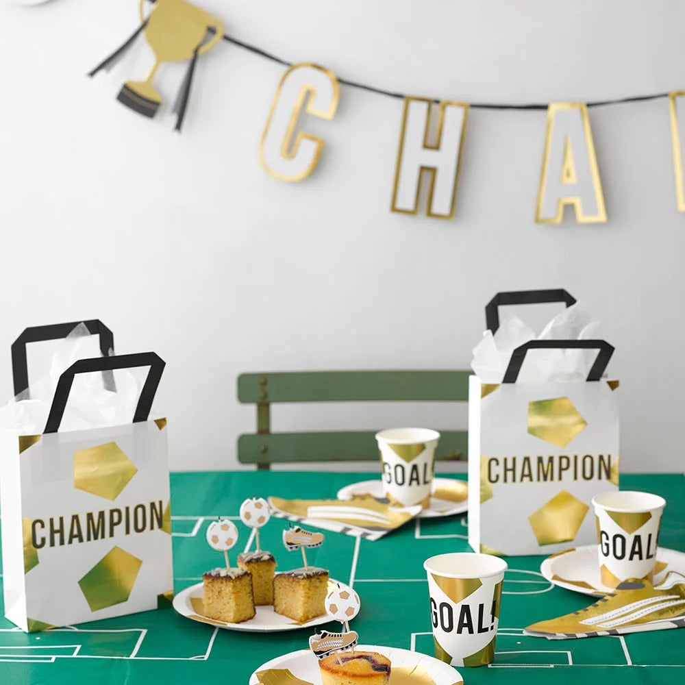 soccer themed table set up with champions party bags, cups and plates