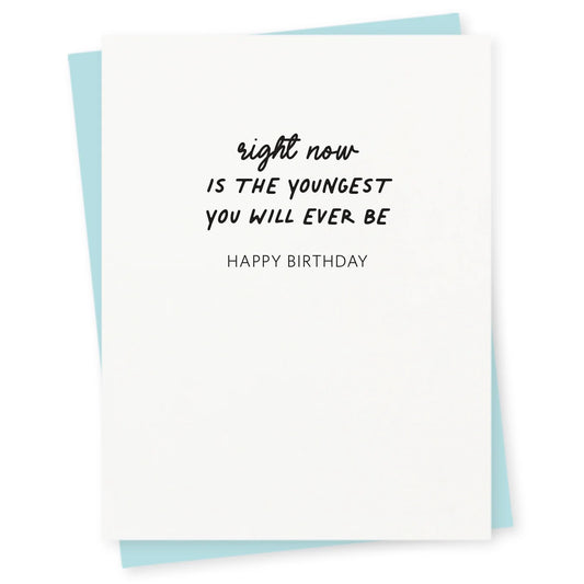 White birthday card with black text reading ‘Right now is the youngest you will ever be. Happy Birthday,’ paired with a light blue envelope.